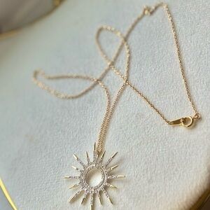 Title: Gold-Tone Sunburst Halo Pendant Necklace – Clear Crystal Accent
